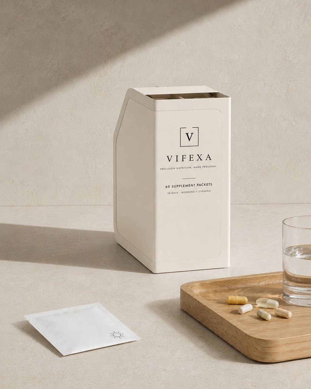 Vifexa monthly box of 60 supplement packets on a counter beside a daily packet, loose capsules, and a glass of water