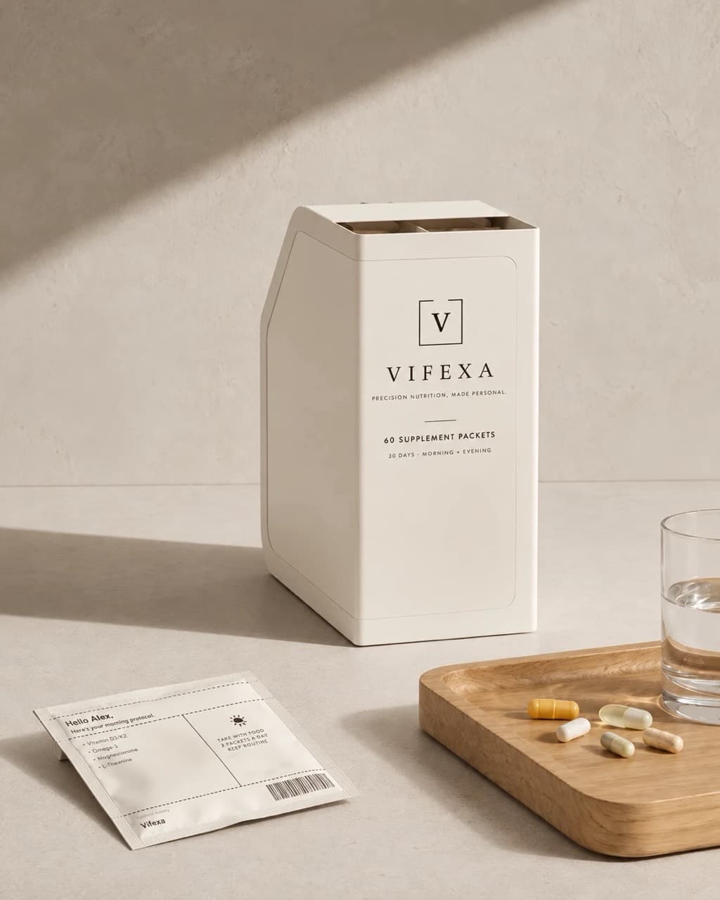 Vifexa monthly box of 60 supplement packets on a counter beside a printed morning packet listing its contents, loose capsules, and a glass of water